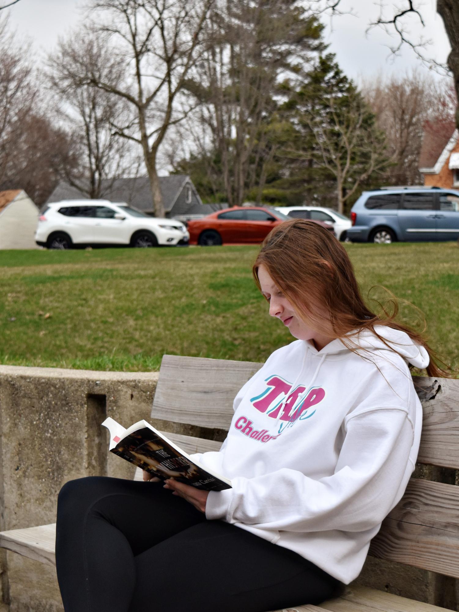 Senior Angie Dubose reads a book on a bench outside the eastern entrances to WEGO.