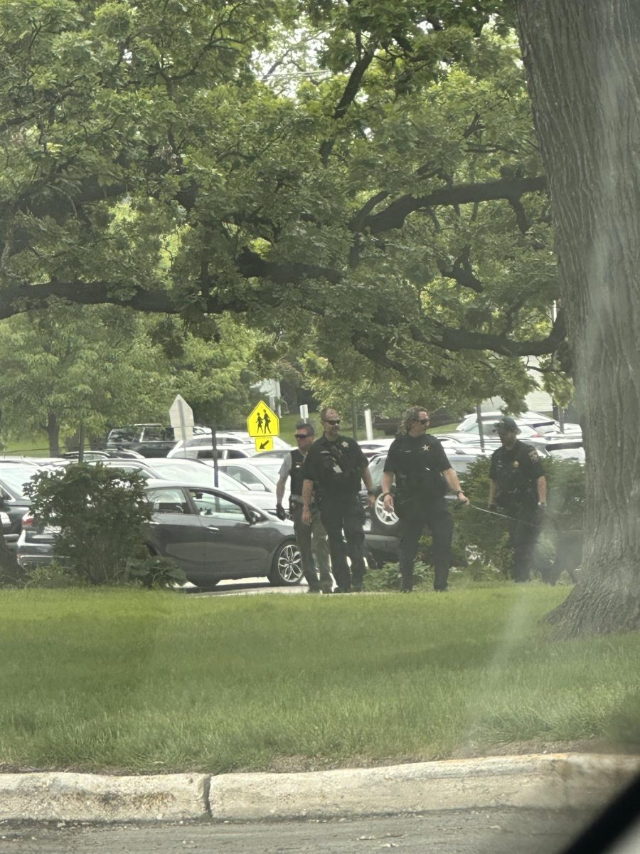 Oficiales de la Policía de West Chicago caminan cerca del exterior de West Chicago Community High School el 19 de mayo mientras investigaban una amenaza reportada que provocó que la escuela entrara en un protocolo SECURE durante los exámenes finales.