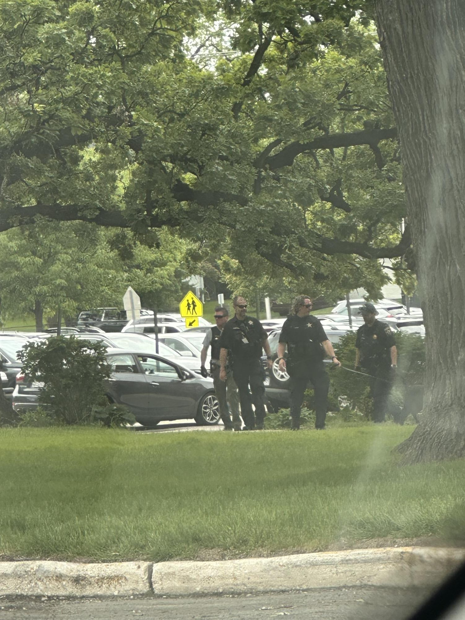 Oficiales de la Policía de West Chicago caminan cerca del exterior de West Chicago Community High School el 19 de mayo mientras investigaban una amenaza reportada que provocó que la escuela entrara en un protocolo SECURE durante los exámenes finales.